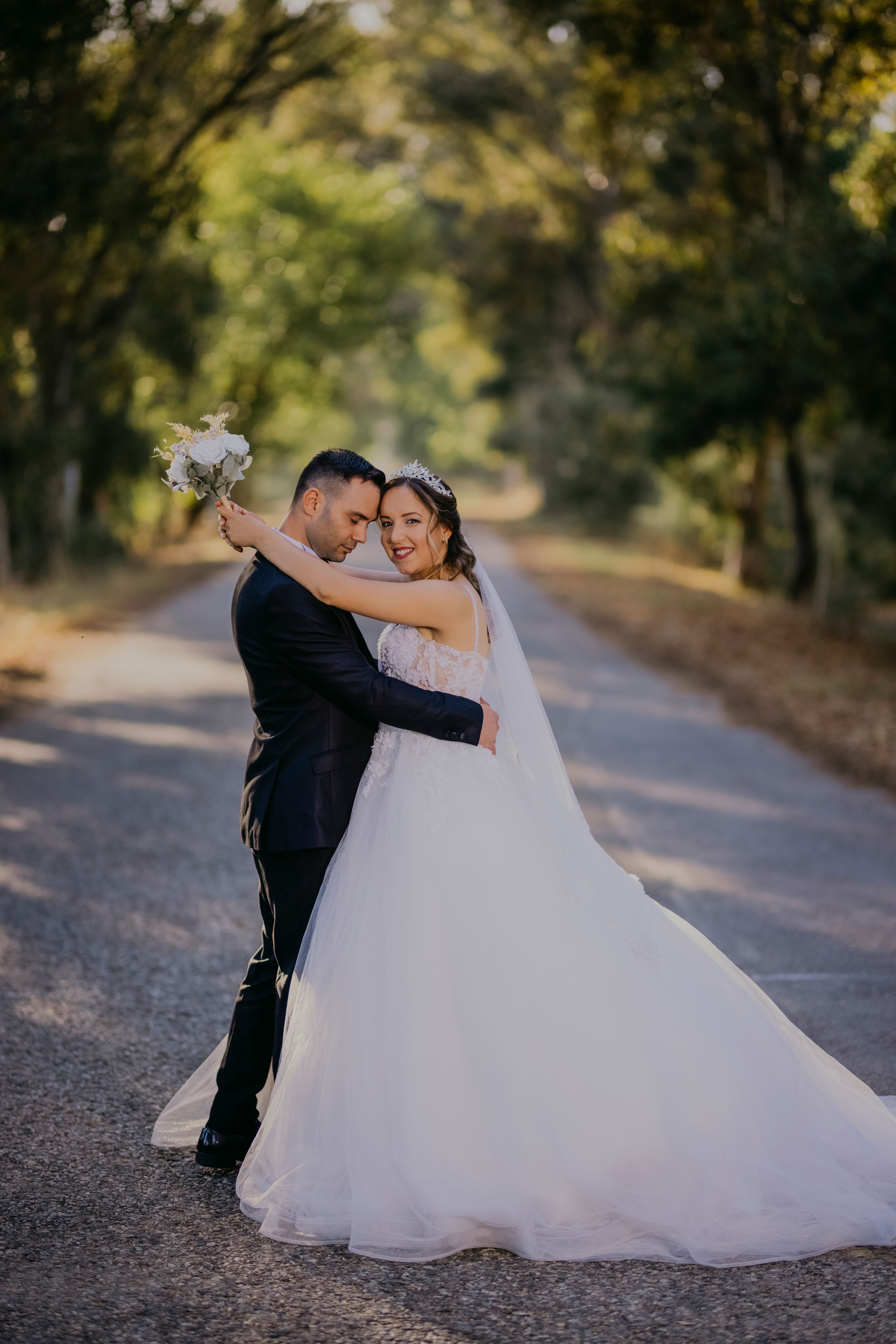 Embracing Newlyweds on Road in Forest · Free Stock Photo