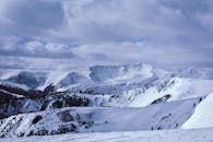 白雪皑皑的山峰在多云天空下令人惊叹，捕捉到了大自然冬季的美丽