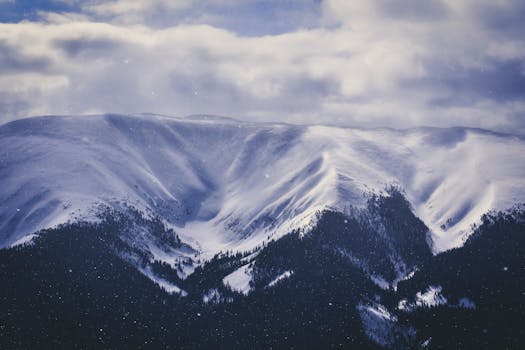 A stunning snowy mountain range under a cloudy winter sky, perfect for nature lovers.