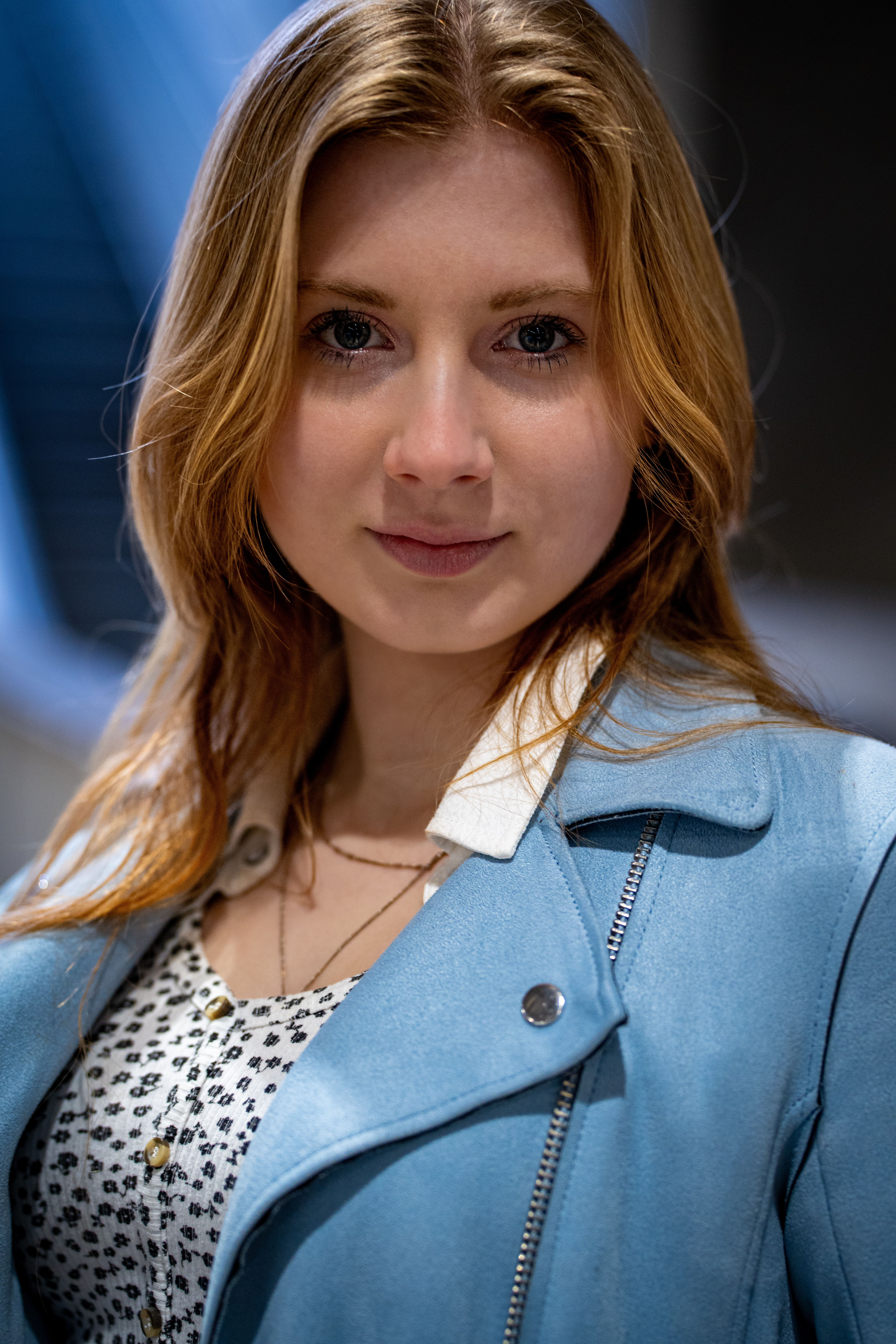 Close-up portrait of a woman with blonde hair posing confidently indoors. Fashionable and stylish.