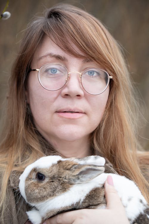 A woman with glasses holding a rabbit
