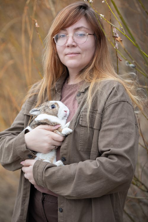 A woman in glasses holding a small rabbit
