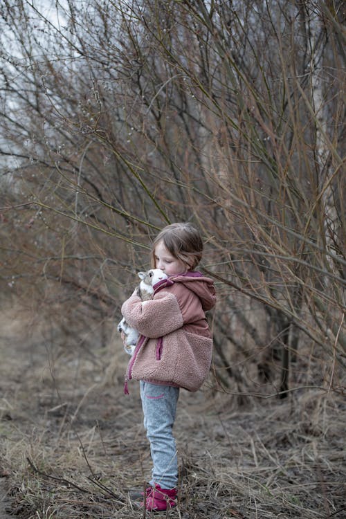 A little girl holding a stuffed animal in the woods