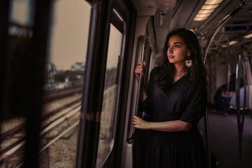 Free Photo of Woman Standing Inside Train Holding on Metal Rail While Looking Outside Stock Photo