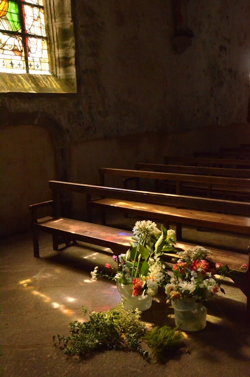 Flowers Placed Beside Brown Wooden Pew Inside Chapel