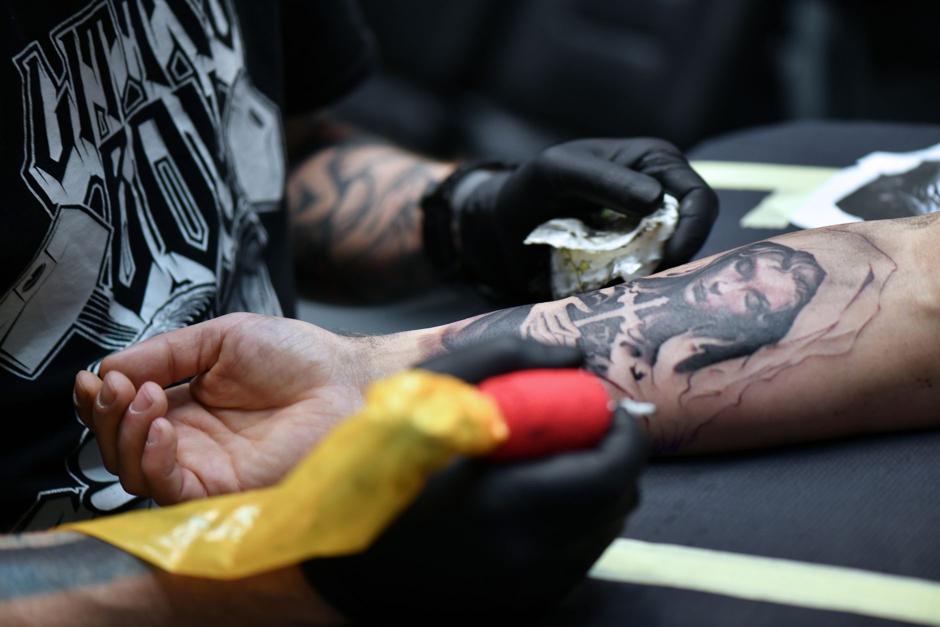 Un tatoueur travaillant sur un design complexe sur le bras avec du matériel de tatouage.
