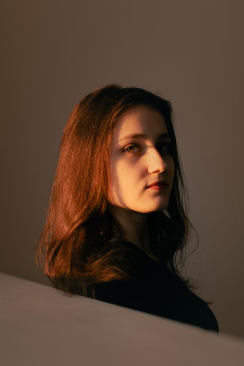 Free A captivating portrait of a woman with sunlit, auburn hair, creating a dramatic shadow effect. Stock Photo