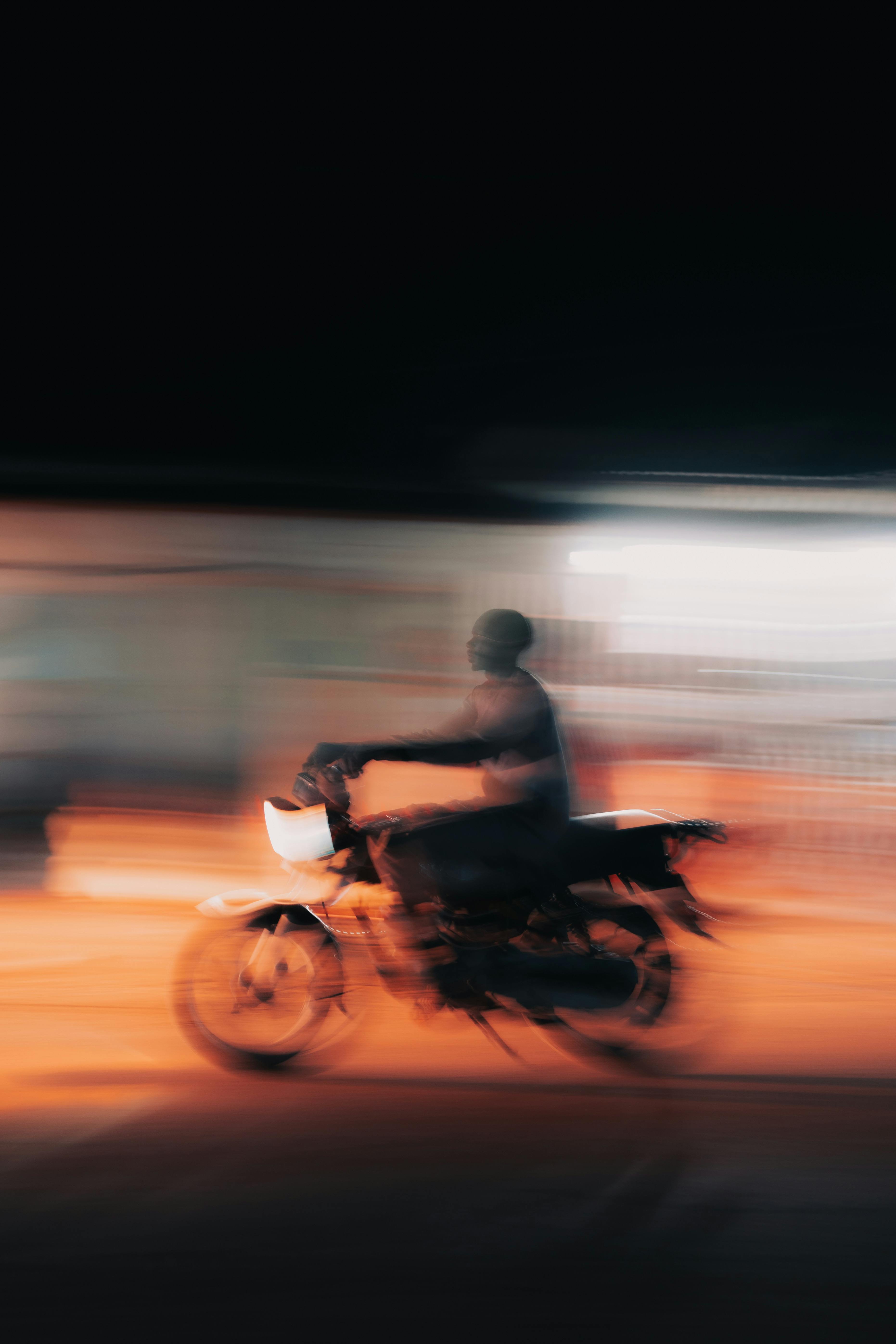 A motorcycle with a rider speeding at night, captured with a vibrant motion blur effect.