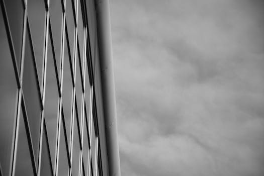 一张现代玻璃建筑立面与多云天空的黑白照片