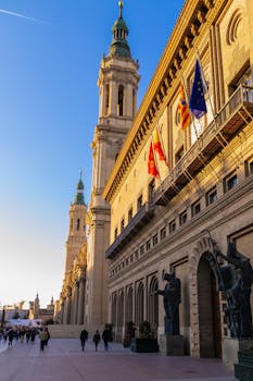 View of historic building with flags and sculptures in Zaragoza, Spain, under a clear blue sky.