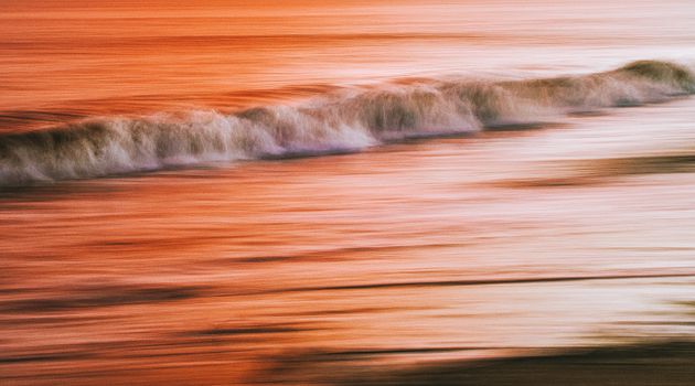 Abstract image of waves in Swansea, Wales with a warm sunset hue.