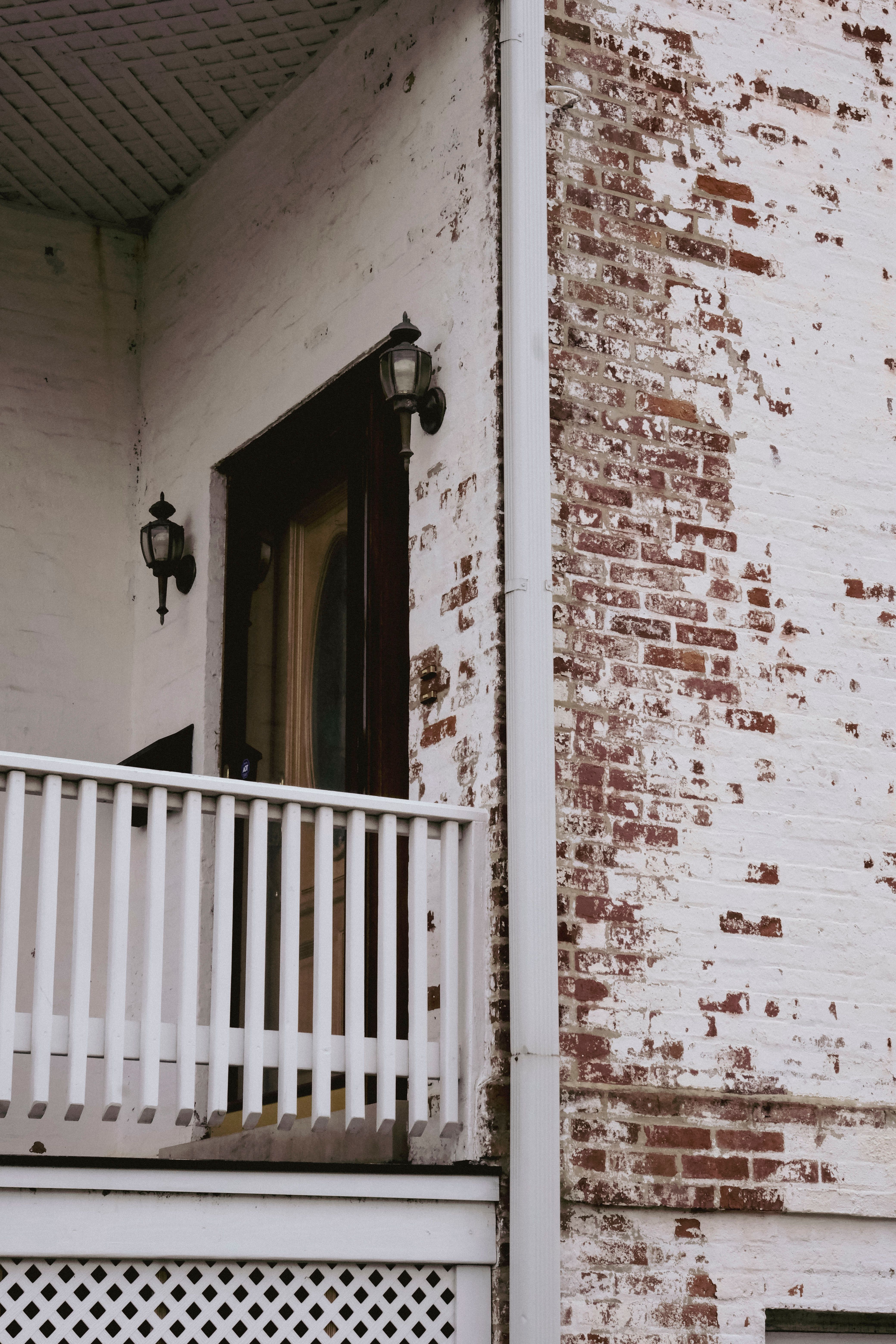 A rustic brick facade with a white railing and vintage style lamps, showcasing an old-world charm.