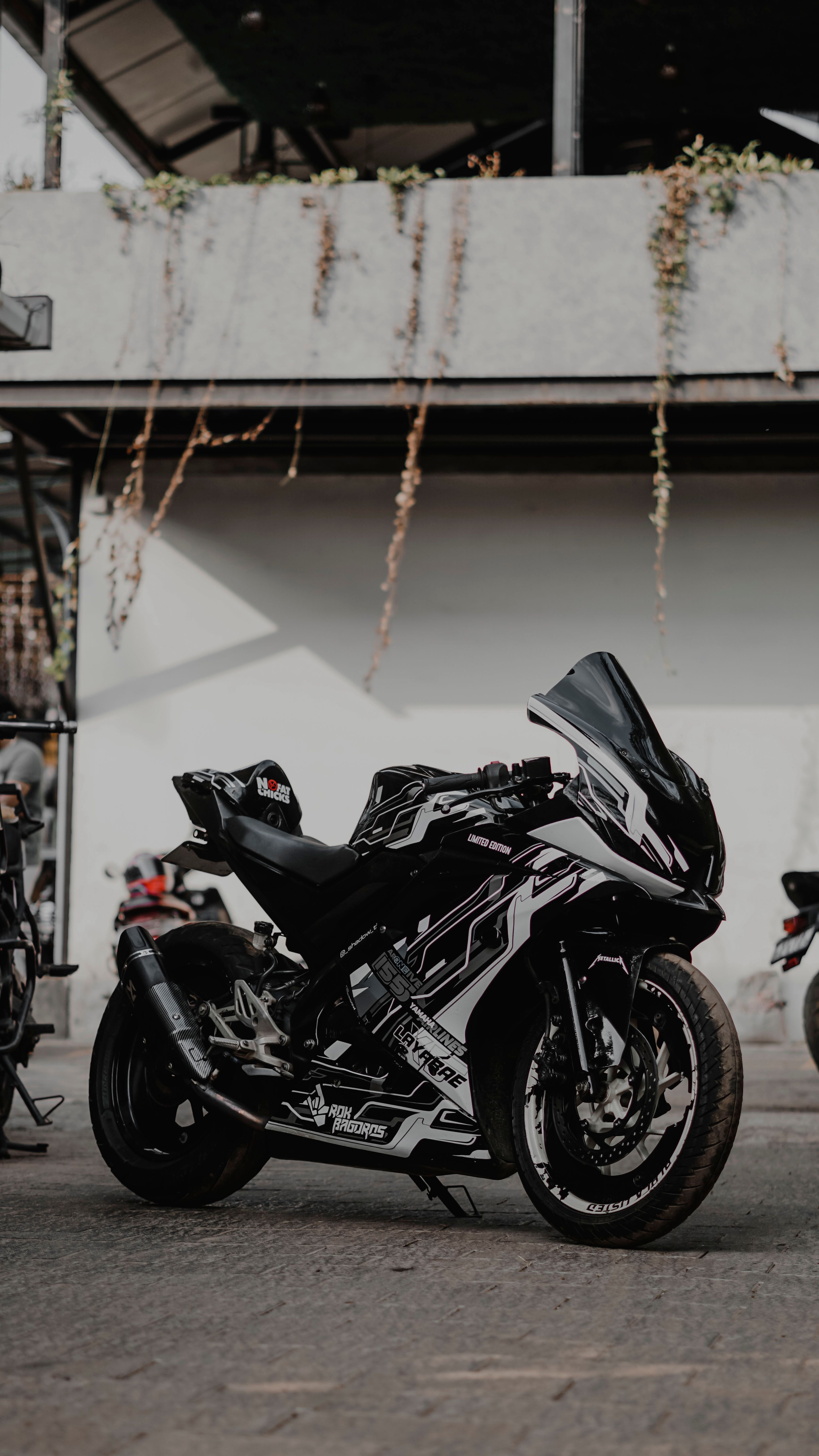 Black sport motorcycle parked in an urban environment with modern architecture in the background.
