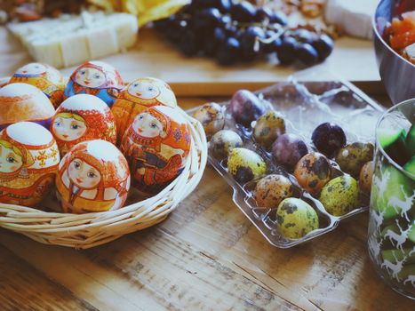 Intricate Easter eggs with Russian designs in a basket, surrounded by colorful quail eggs.