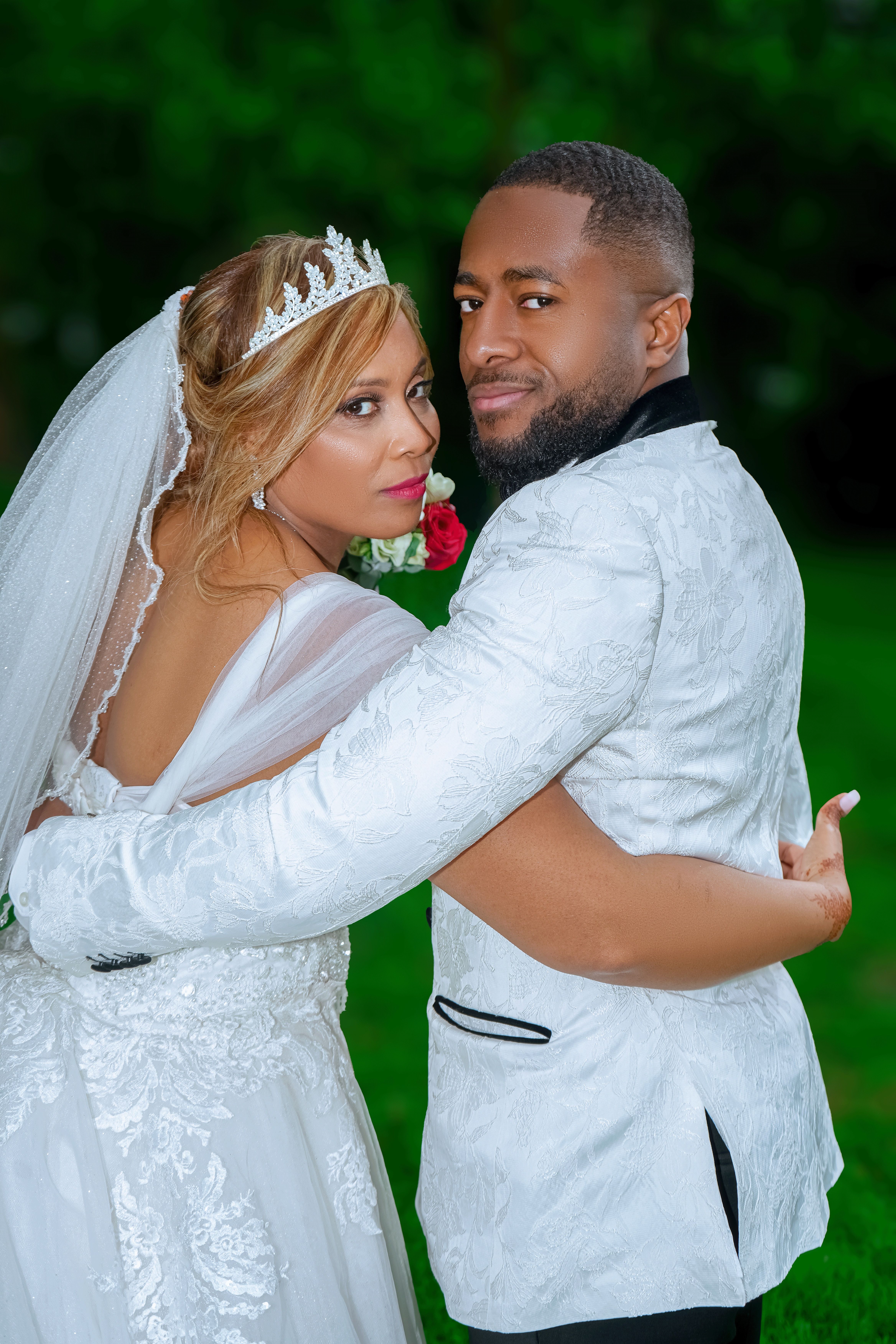 A bride and groom pose for a photo in the grass · Free Stock Photo