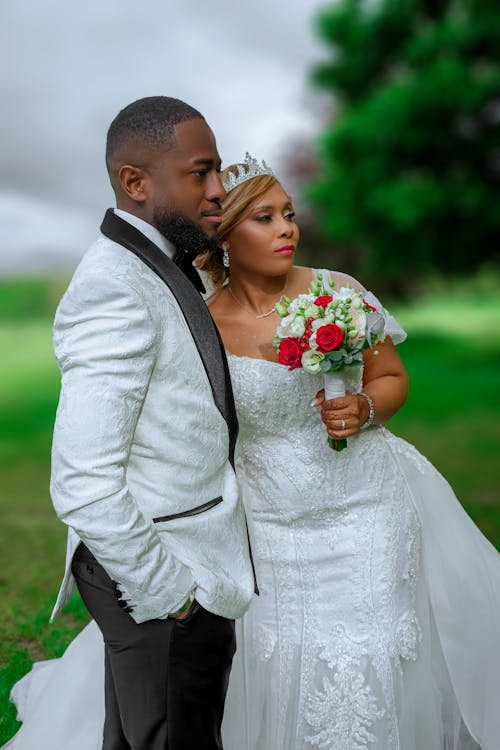 A bride and groom pose for a photo in the grass