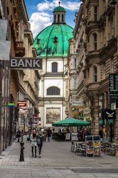 Busy pedestrian street in Vienna's historic district with view of St. Peter's Church dome. by Pixabay