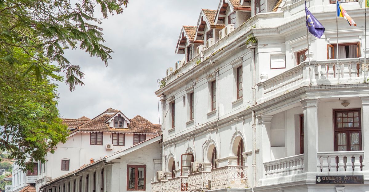 Lively street scene with colonial-era buildings and tuk-tuks in Kandy, Sri Lanka.