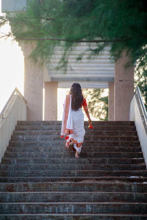 A woman walking down some stairs in white and orange