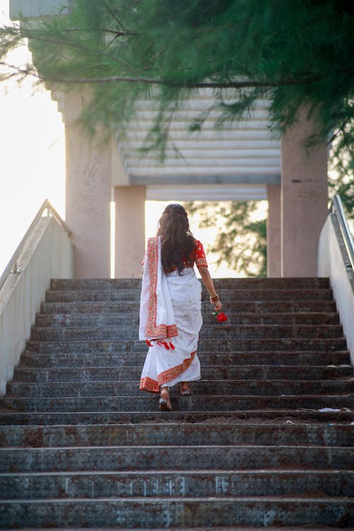A woman in white sari walking down stairs