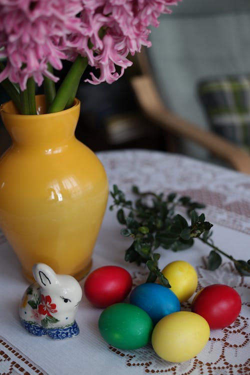 A vase with flowers and a bunch of easter eggs