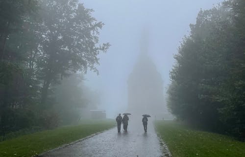 Two people walking in the fog with a monument in the background