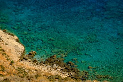 Free Stunning aerial view of rocky shoreline meeting clear turquoise water, perfect for nature and travel themes. Stock Photo