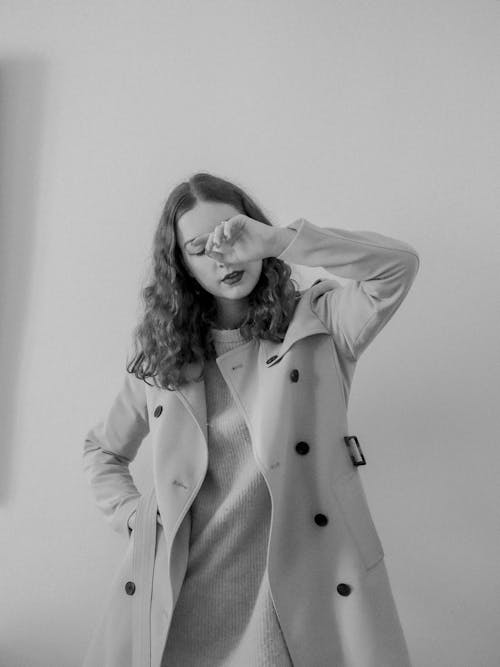 A woman in a trench coat is posing for a photo