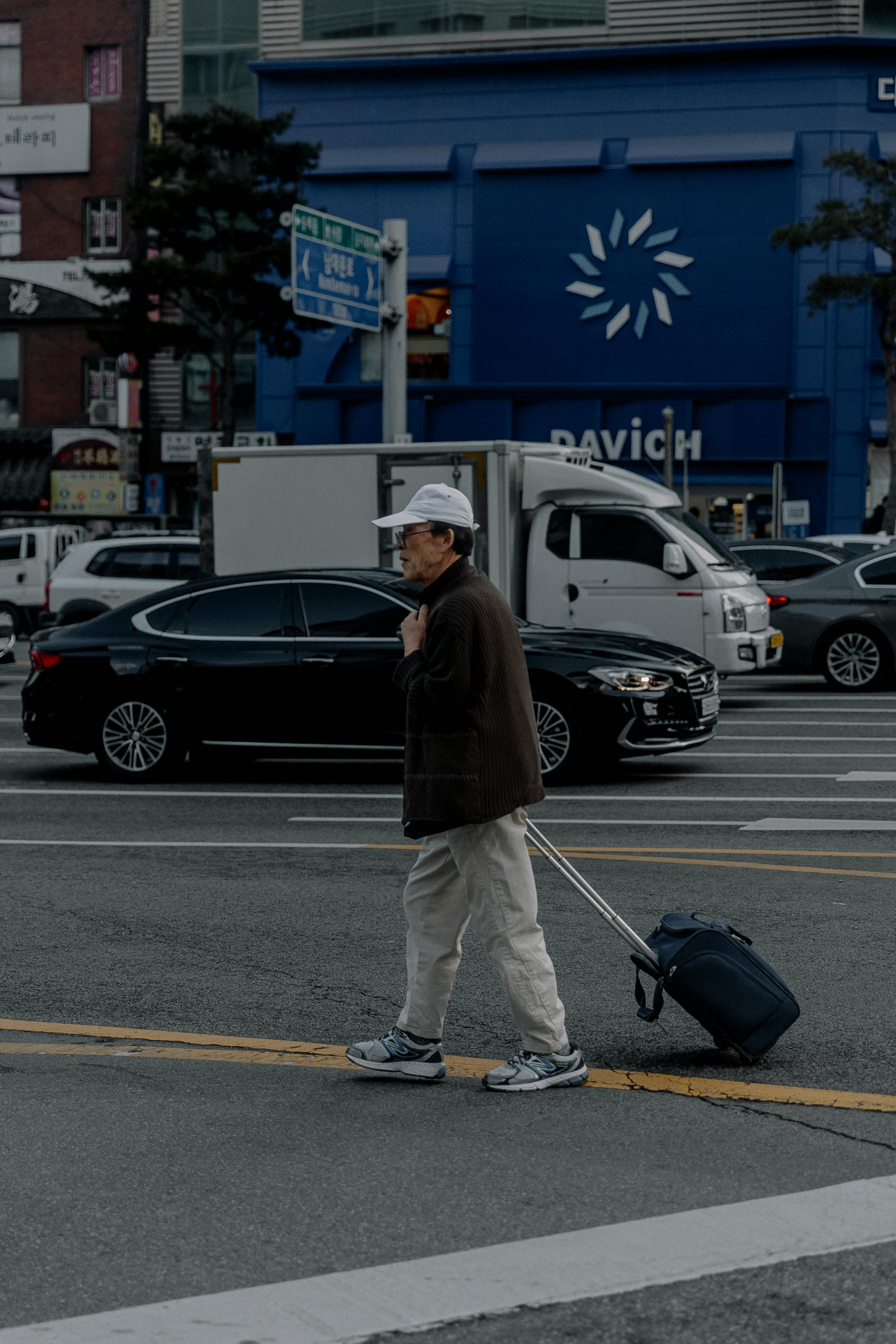 Man with luggage crossing a bustling city street in Tokyo, Japan, showcasing urban travel.