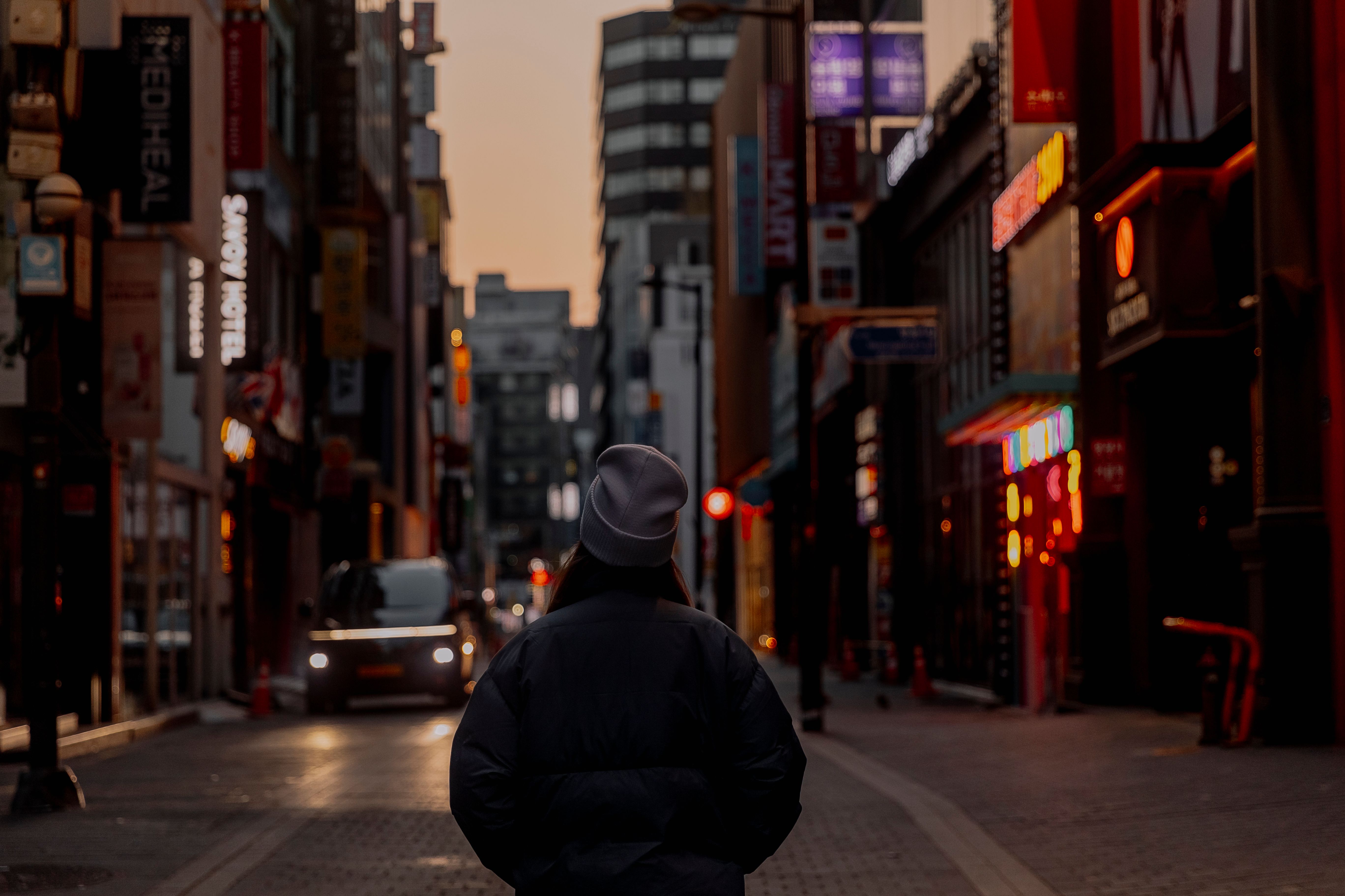 A person walking down a city street at night · Free Stock Photo