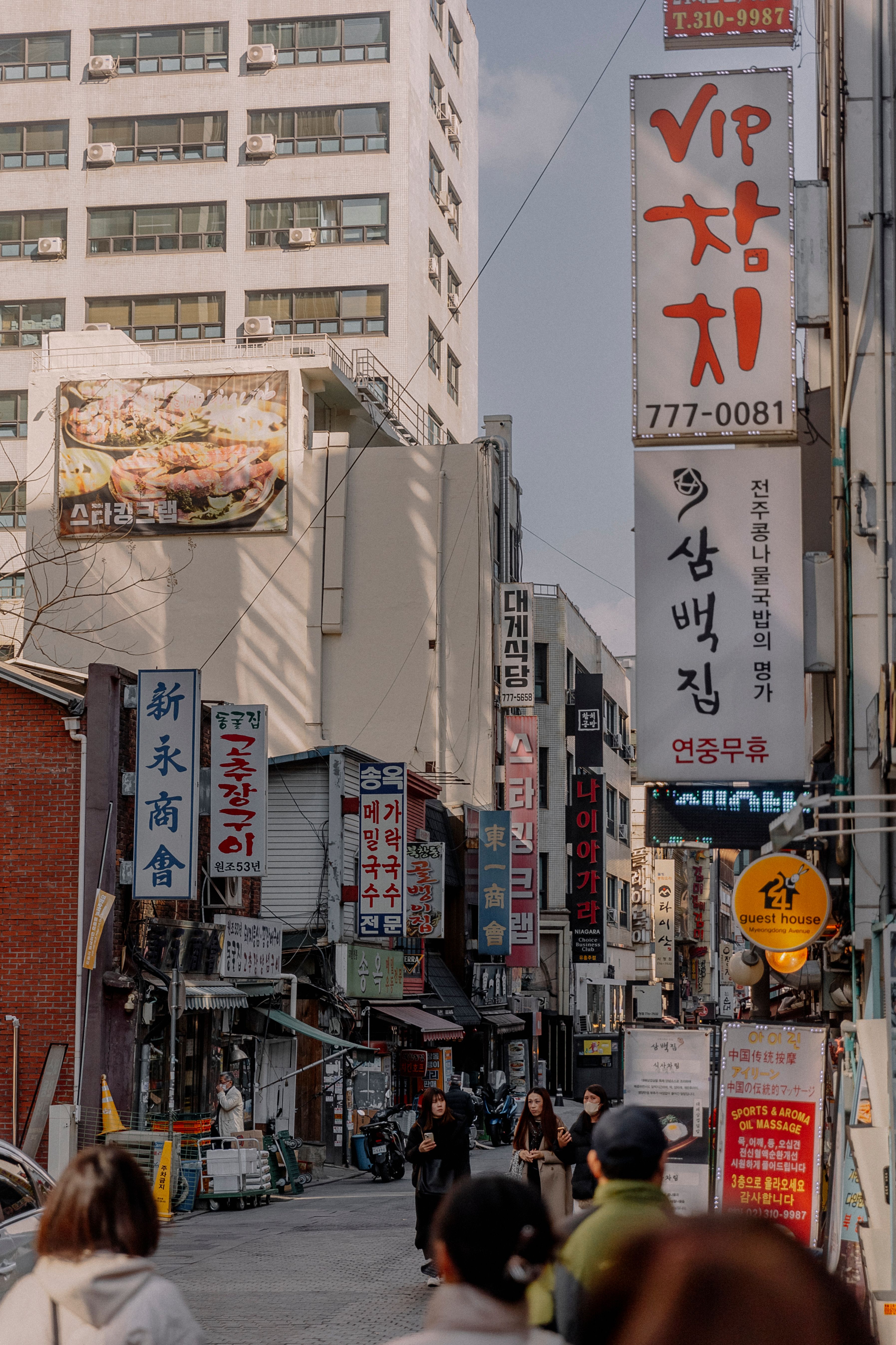 Dynamic street scene in a Korean city with shops, signs, and pedestrians, showcasing vibrant urban life.