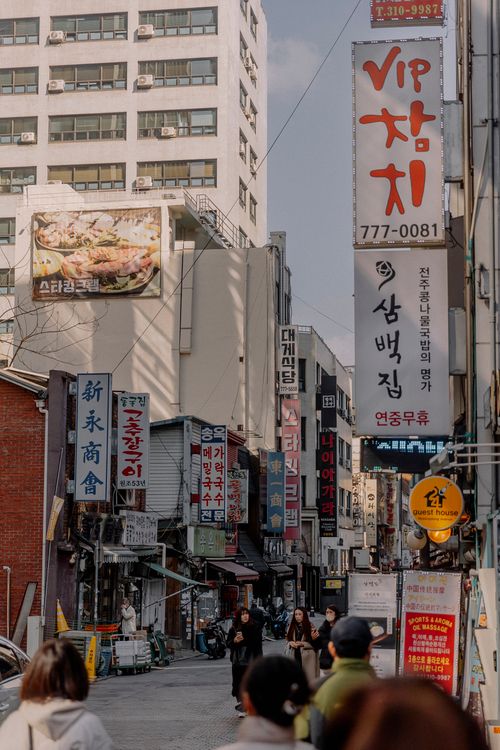 Free Dynamic street scene in a Korean city with shops, signs, and pedestrians, showcasing vibrant urban life. Stock Photo