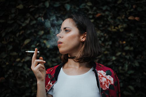 Woman In White Top And Red Floral Jacket Smoking Cigarette