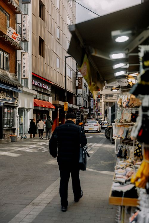 Free A pedestrian walks through a vibrant city market street, creating a bustling urban atmosphere. Stock Photo