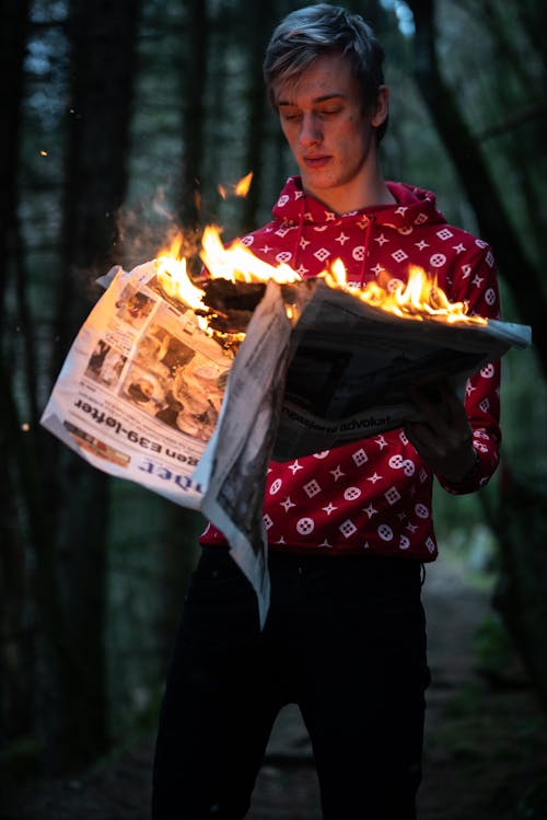 Man Holding Burning Newspaper