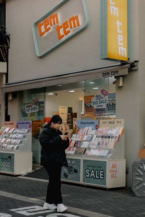 A woman is walking down the street in front of a store