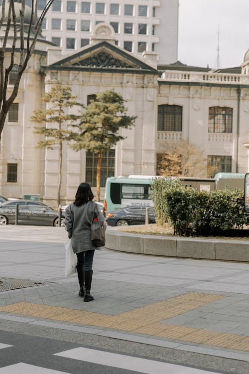 A woman walking down the street in front of a building