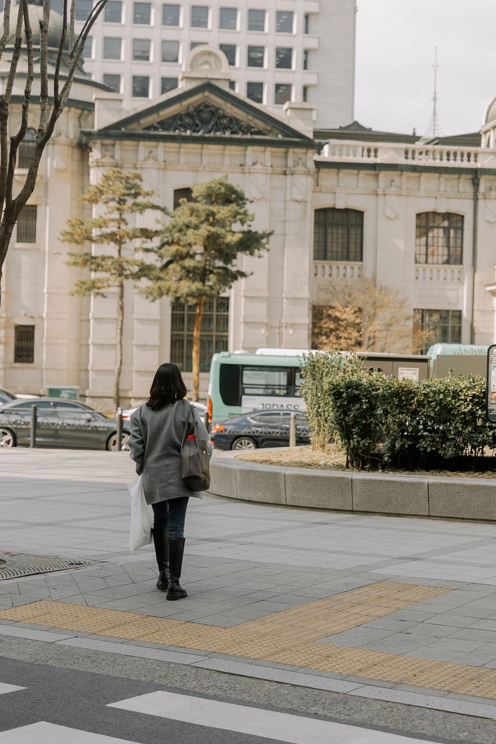 Woman walking past historic buildings and urban scenery on a Seoul street