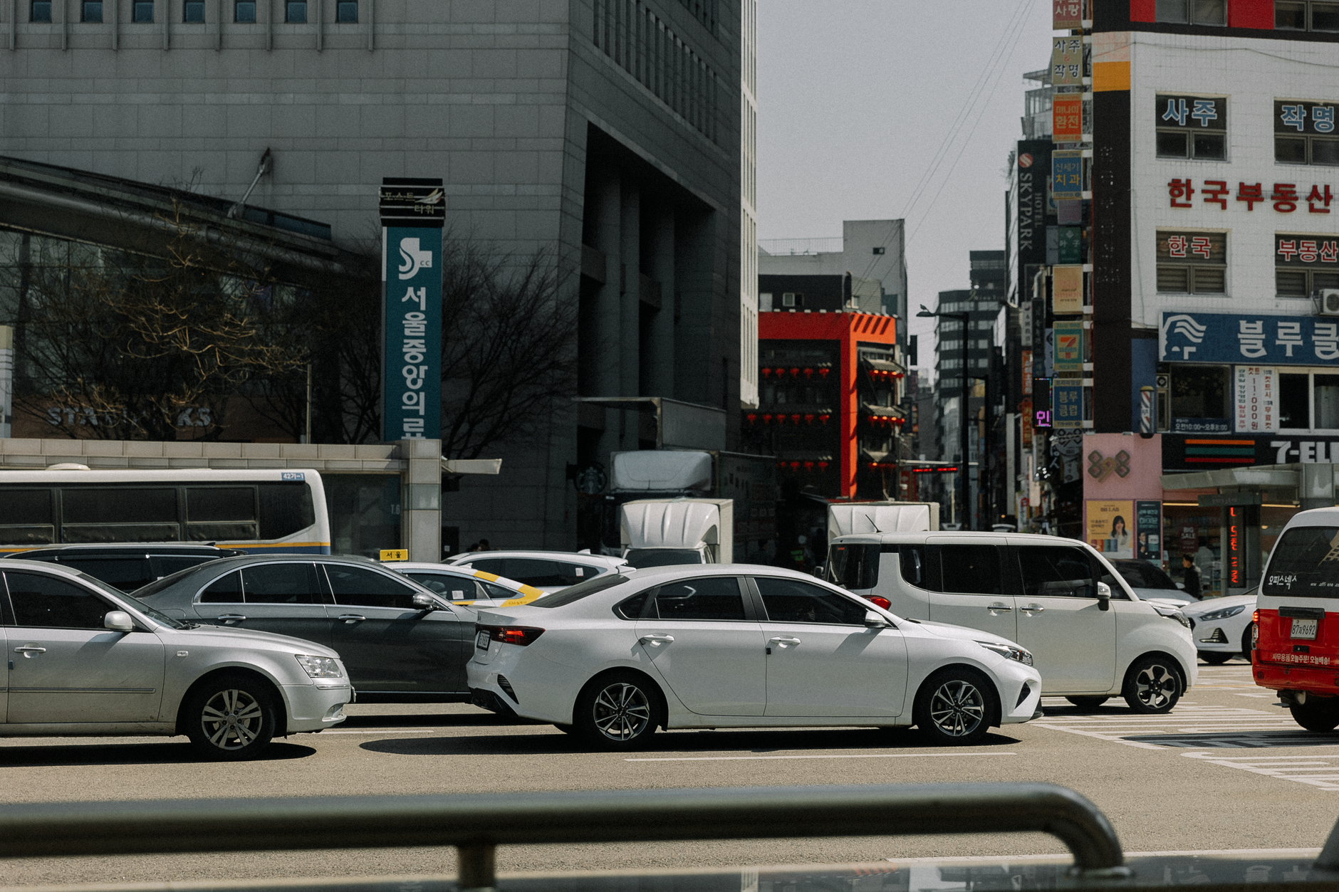A busy urban intersection with cars and modern buildings on a sunny day.
