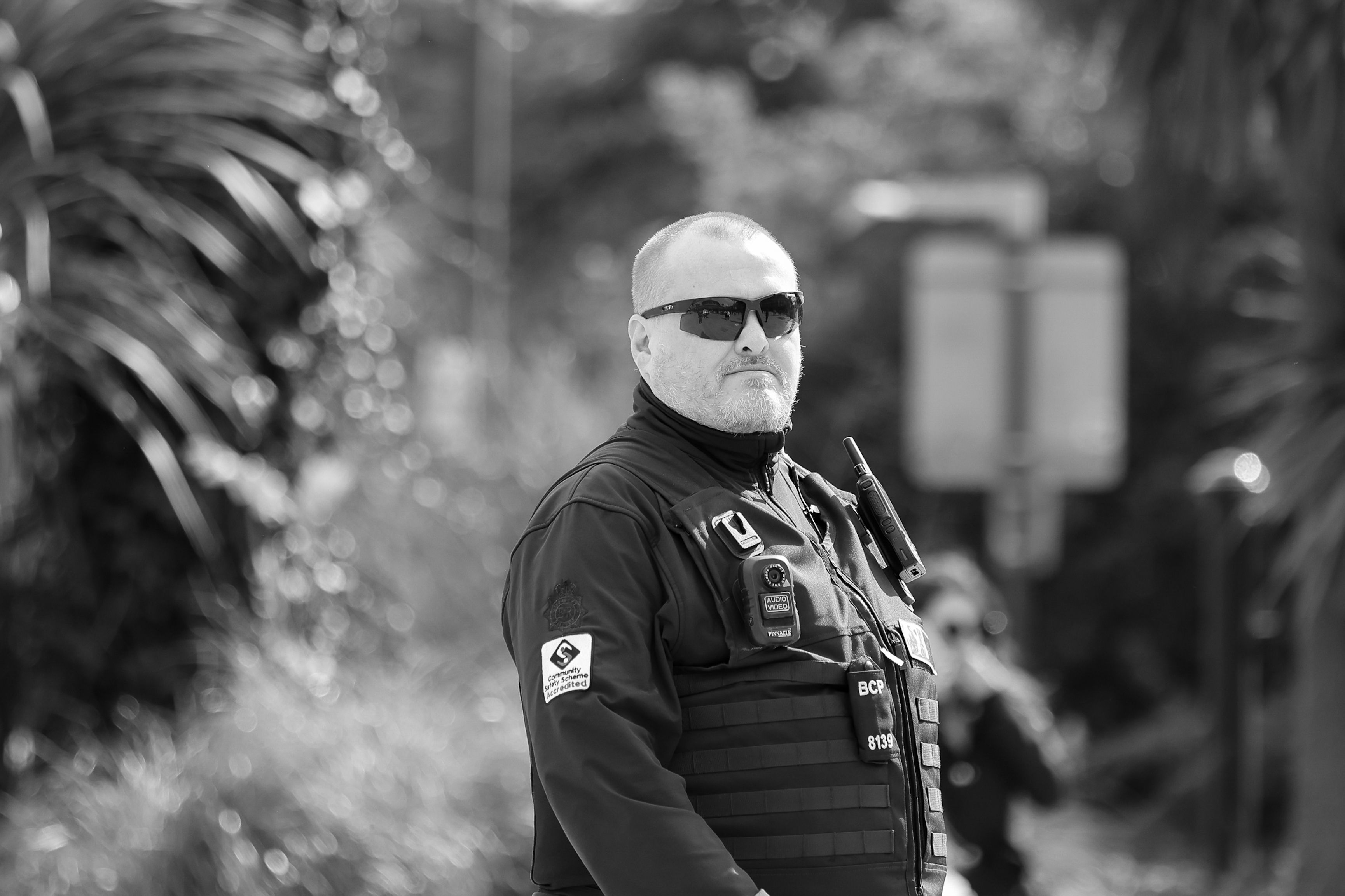 A man in sunglasses and a jacket standing on the street