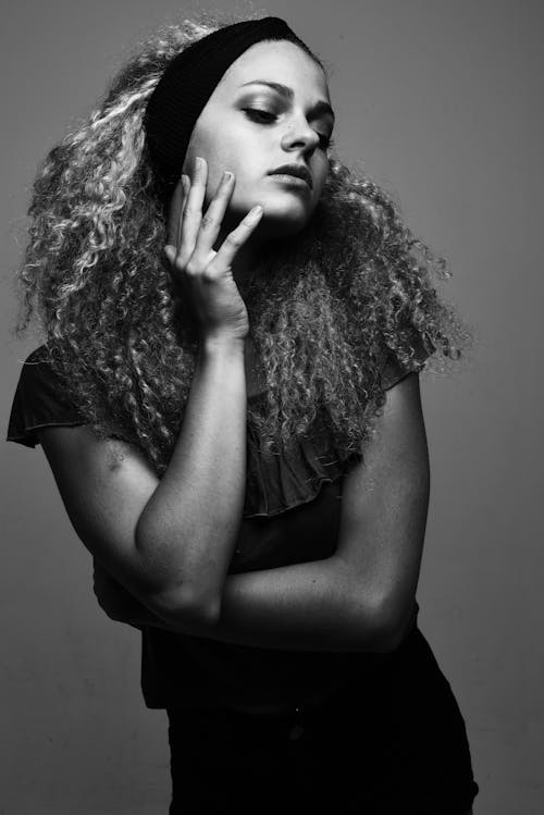 A woman with curly hair posing for a black and white photo