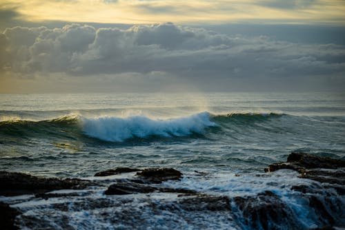 A wave crashing on the rocks at sunset