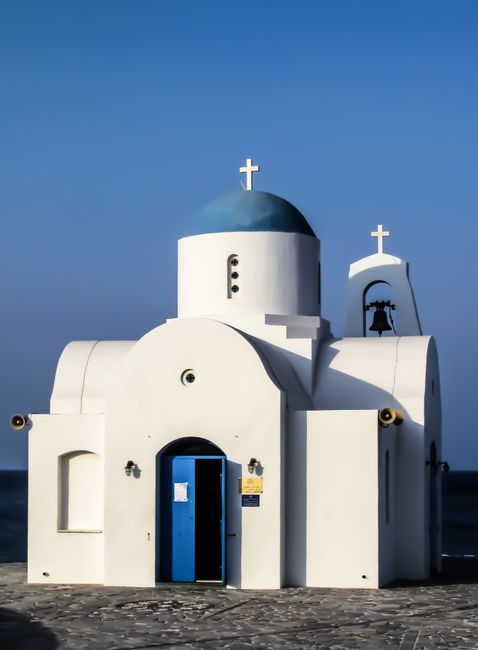 A picturesque white chapel with a blue dome and crosses under a clear blue sky, symbolizing spirituality.