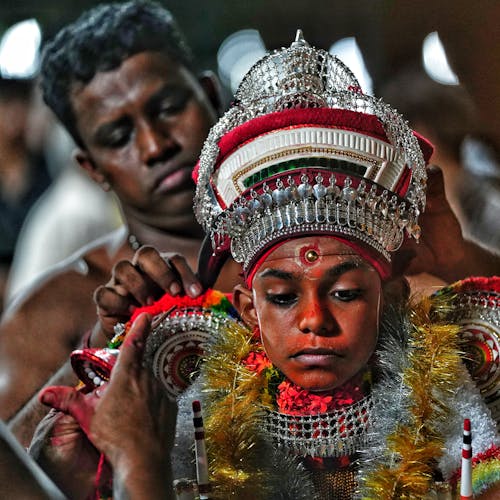 A man in a traditional costume is getting his hair done