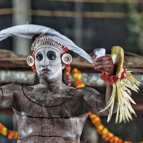 A man in a costume with white face paint and feathers