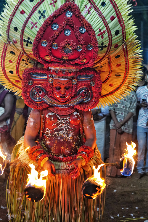 Free Colorful traditional Theyyam dance in India featuring vibrant costume and flames. Stock Photo