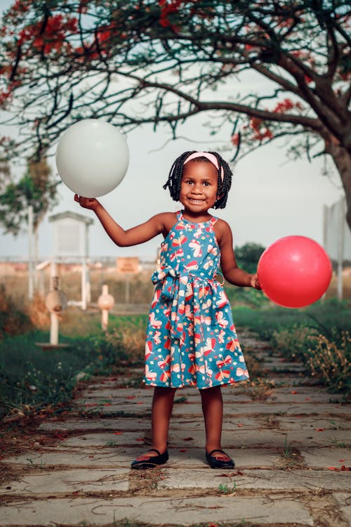 Little Girl Holding Balloons in a Garden