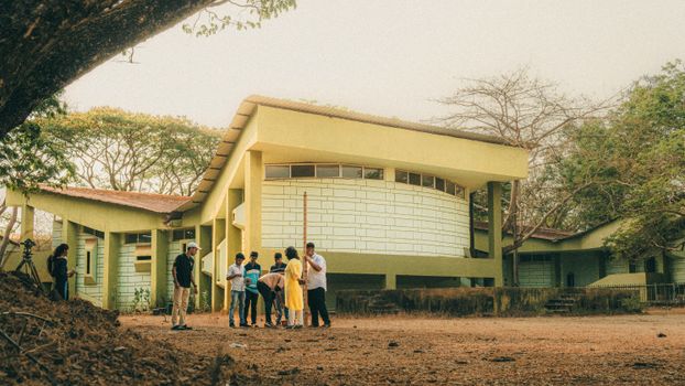 A small group of people having a meeting near a modern building surrounded by trees.