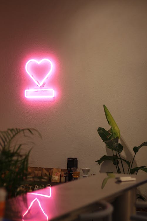 Free A neon sign with a heart on it is on a wall Stock Photo