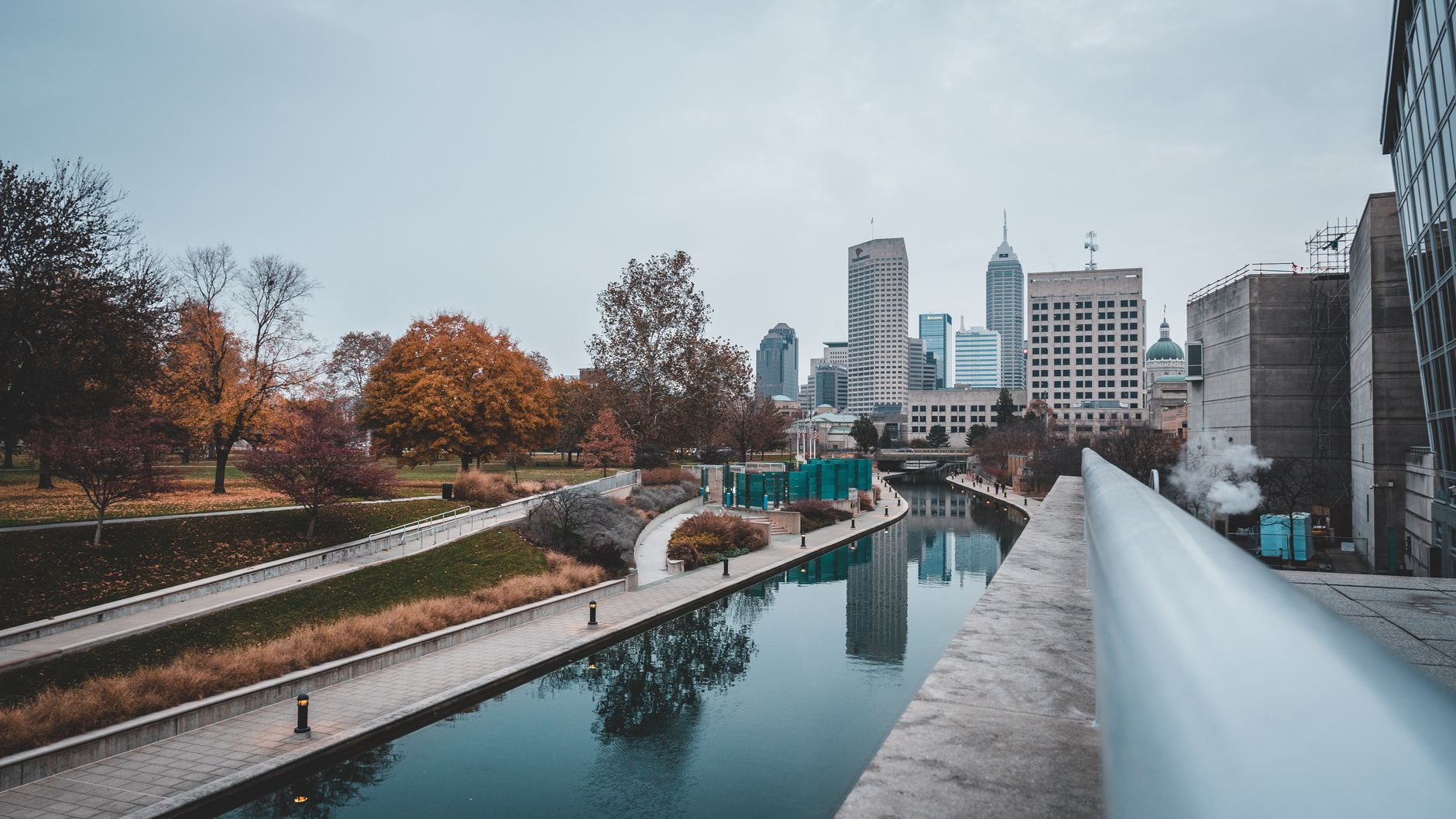 Scenic view of Indianapolis canal with city skyline and autumn colors reflecting on the water.